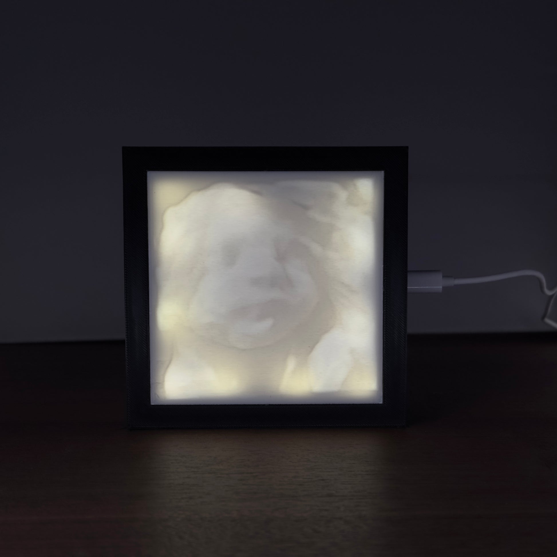 Verlicht fotoframe met een 3D-geprinte lithofane van een 3D-echo – toont het gezicht van een ongeboren baby in sfeervol licht.